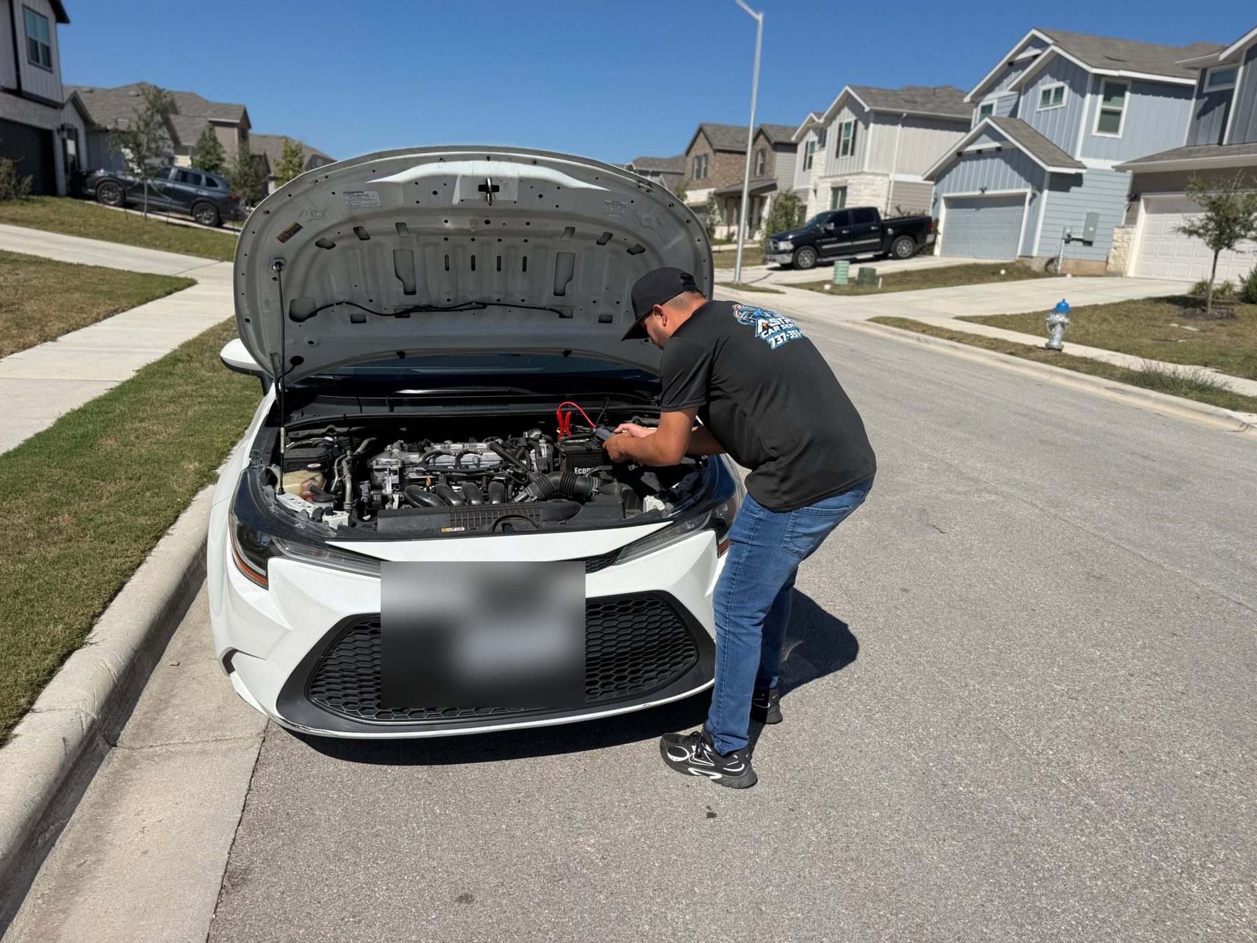Astro Roadside technician jump-starting a car on a residential street in Austin